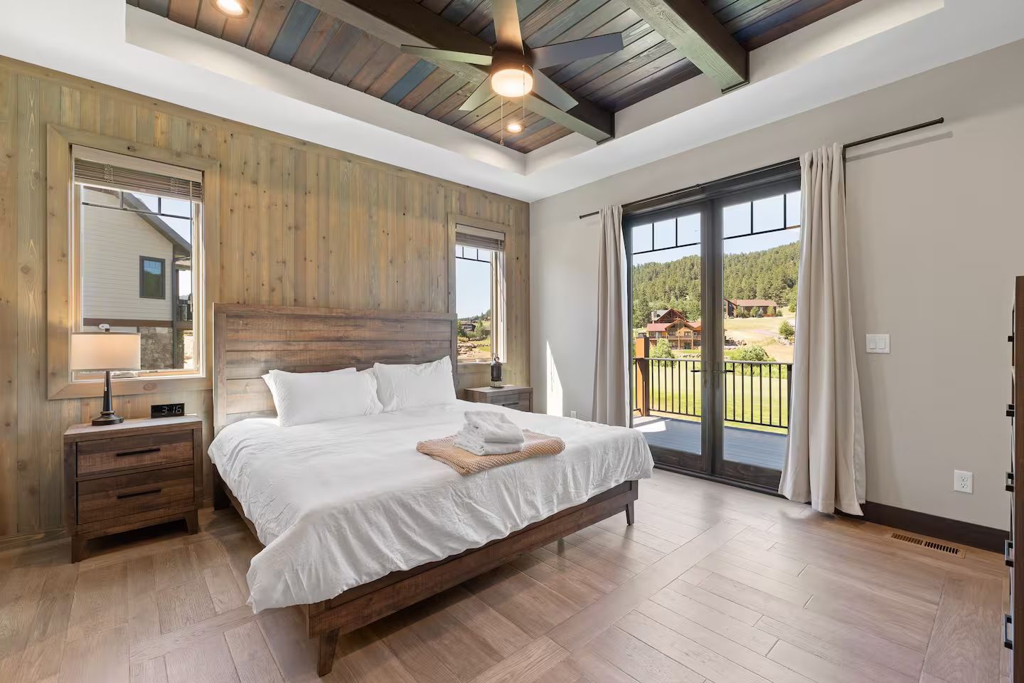 King bedroom with a wood accent wall, a coffered ceiling and French doors to the deck