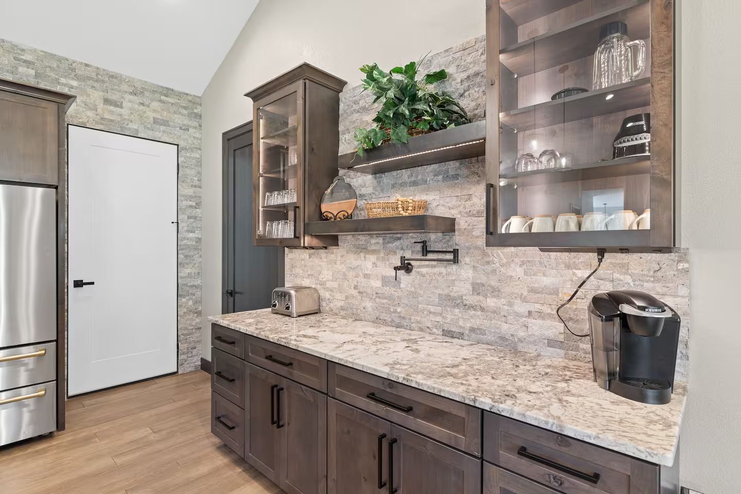 Coffee bar with a Keurig, a pot filler, floating shelves and glass-front cabinets