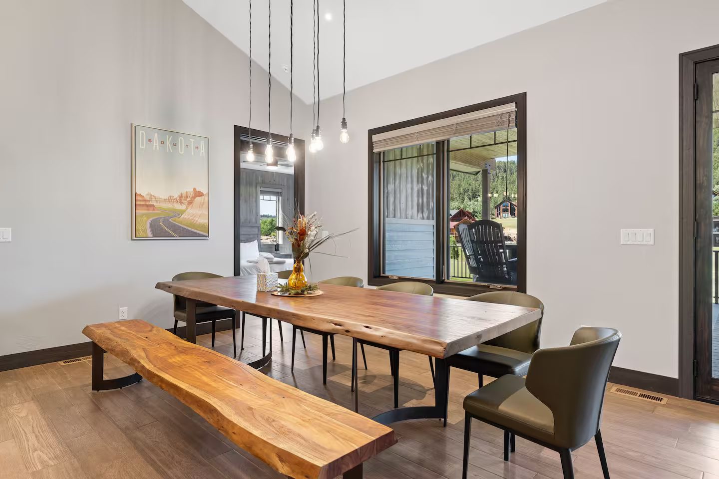Live-edge wood dining table with a matching bench and upholstered chairs under pendant lights