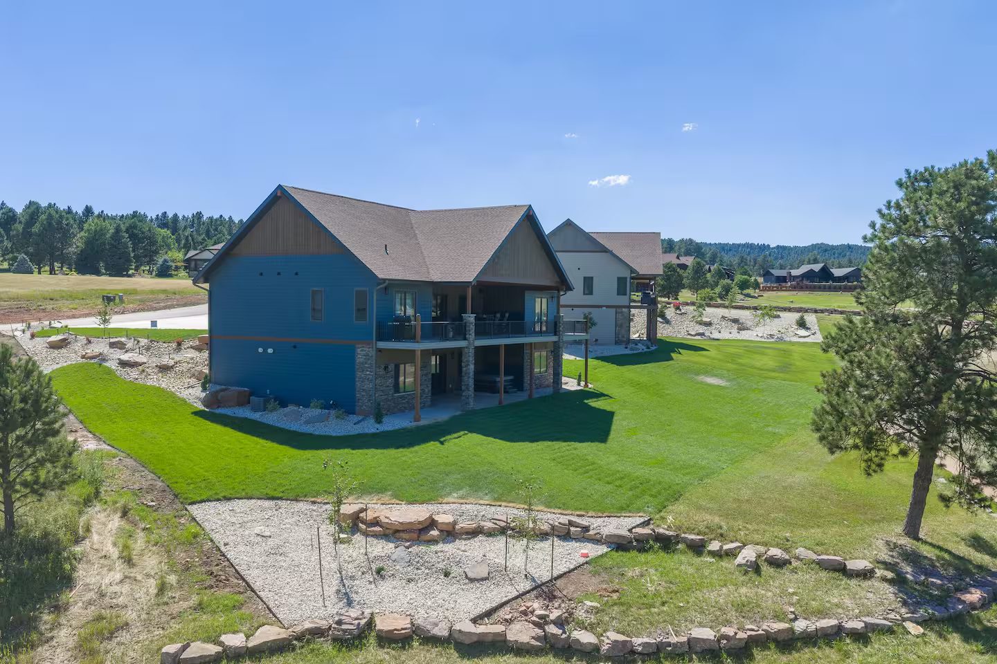 The home from the course, with its neighbor beyond, across new lawn and landscaping