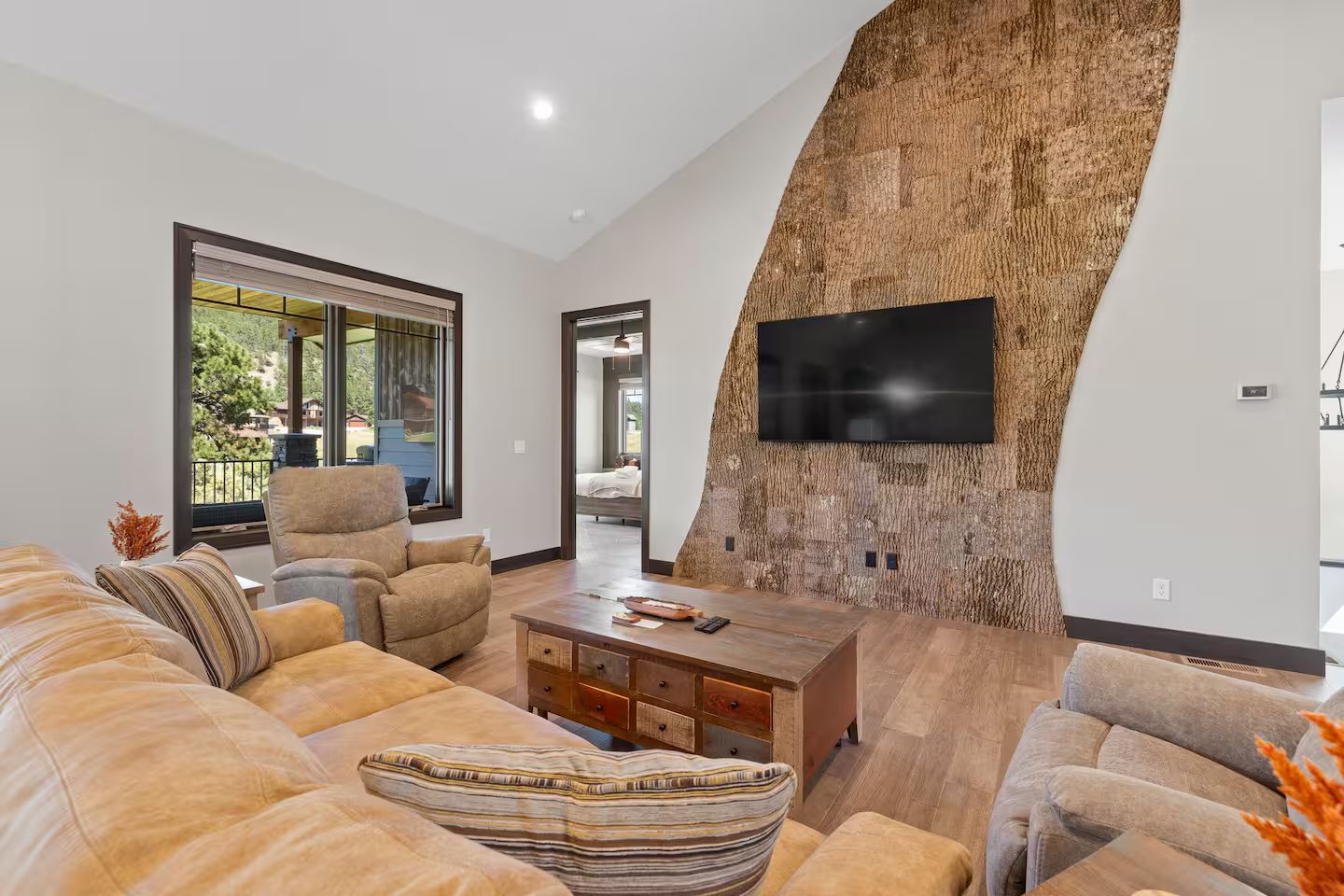 Great room with leather sofas and a TV on a curved, bark-textured feature wall
