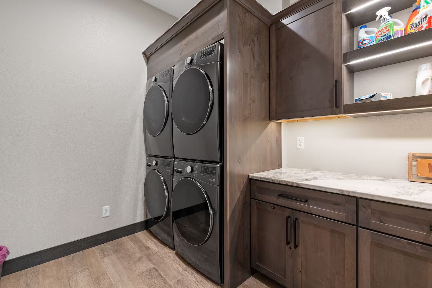 Laundry room with two stacked washer and dryer sets and wood cabinets