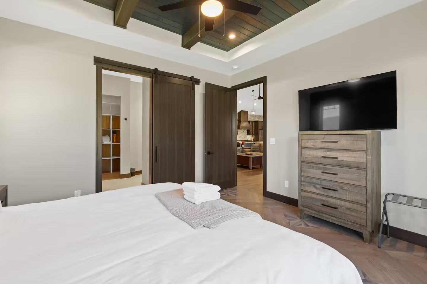 King bed facing a dresser with a TV and a sliding barn door