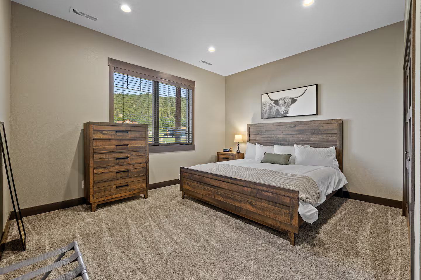 Carpeted king bedroom with a wood bed frame and a dresser